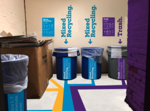 Image of both mixed recycling and trash waste bins in a garbage room on campus. 